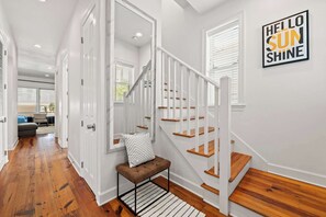 A staircase with white railings and wooden steps, a bench with a patterned cushion, and a 'Hello Sun Shine' sign on the wall. - Salt & Sol Free Golf Cart Pool Heat Deals (Destin)