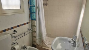 A bathroom with a toilet, bidet, bathtub, and sink.