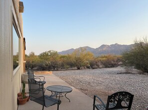 Eine Terrasse mit Gartenmöbeln, einer Kakteepflanze und Blick auf Berge.