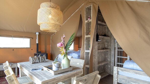 Ein Zeltdom-Unterkunft mit einem Holztisch, Stühlen, einer Hängelampe und einem Bett mit Blick.