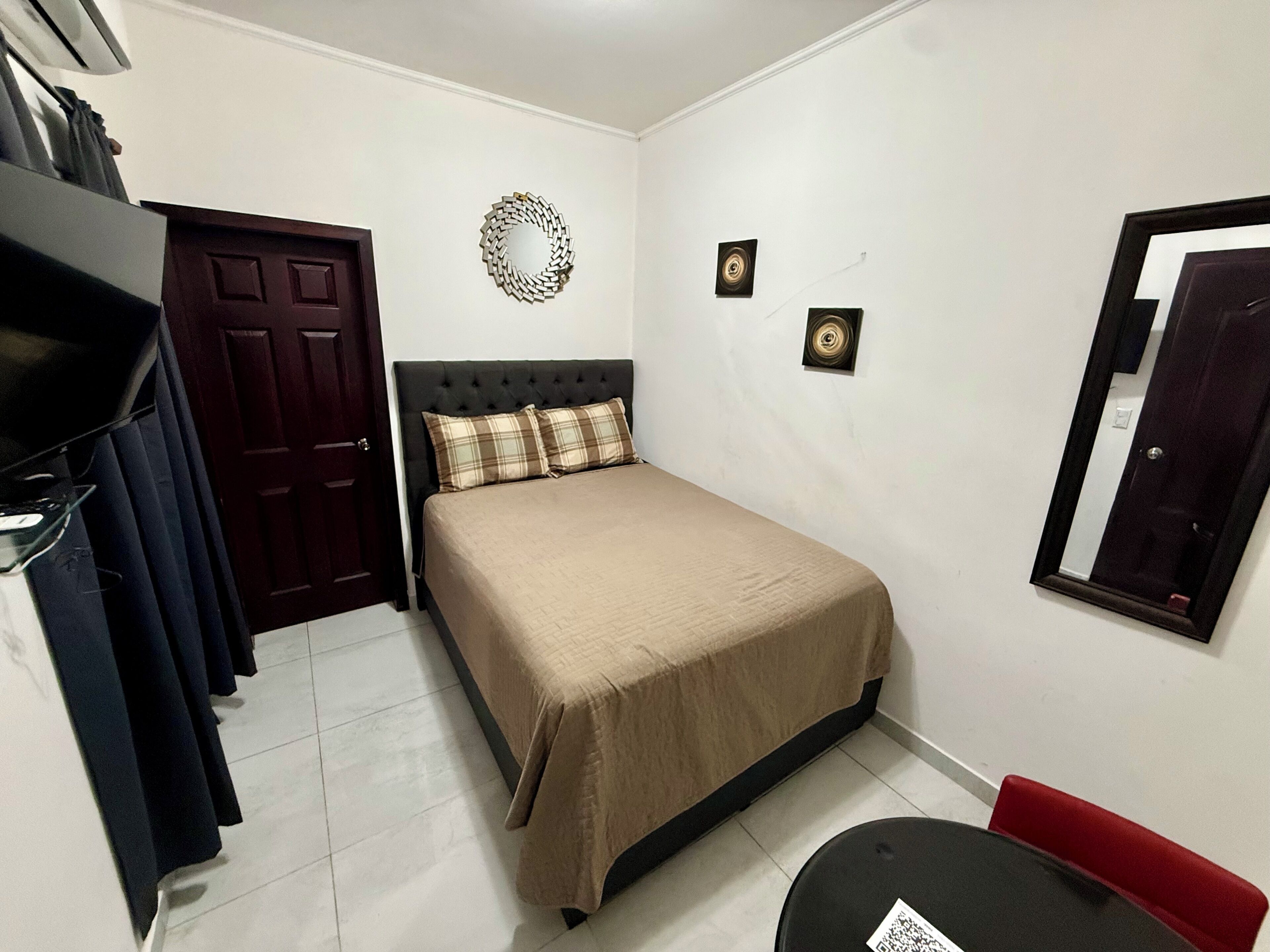 Un dormitorio con cama, armario, espejo y puerta.