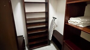 Ein begehbarer Kleiderschrank mit offenen Regalen, einer Kleiderstange und einem gefalteten Handtuch auf einem Regal.