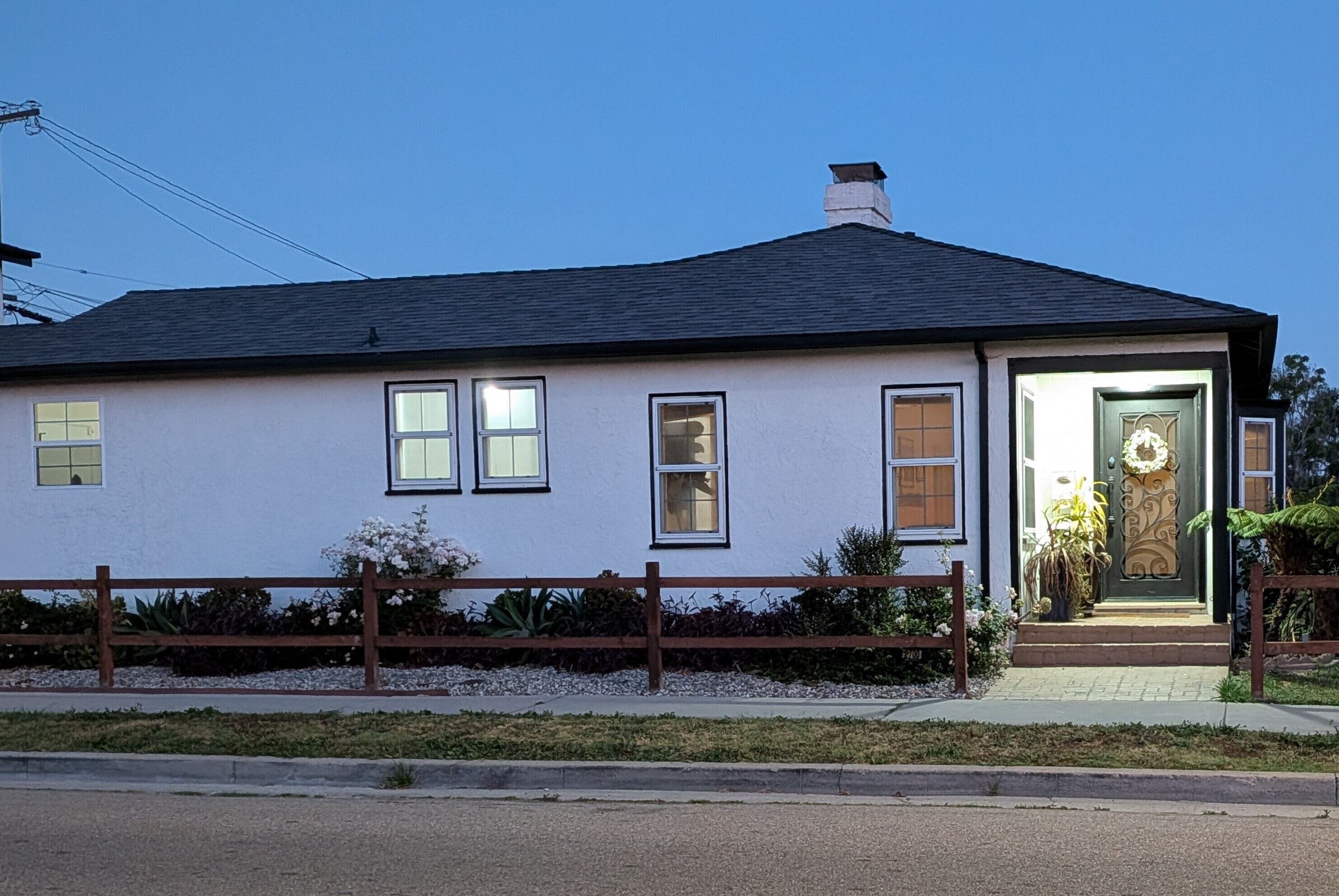 A single-story house with a dark roof, white walls, and a front door with a decorative design.