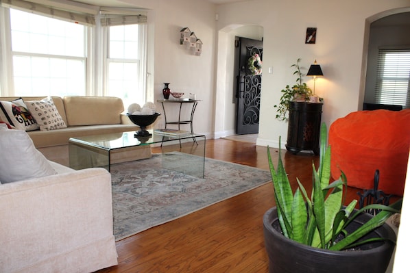 Un salon avec un canapé, une table basse, une plante en pot et une porte décorée d’une guirlande.