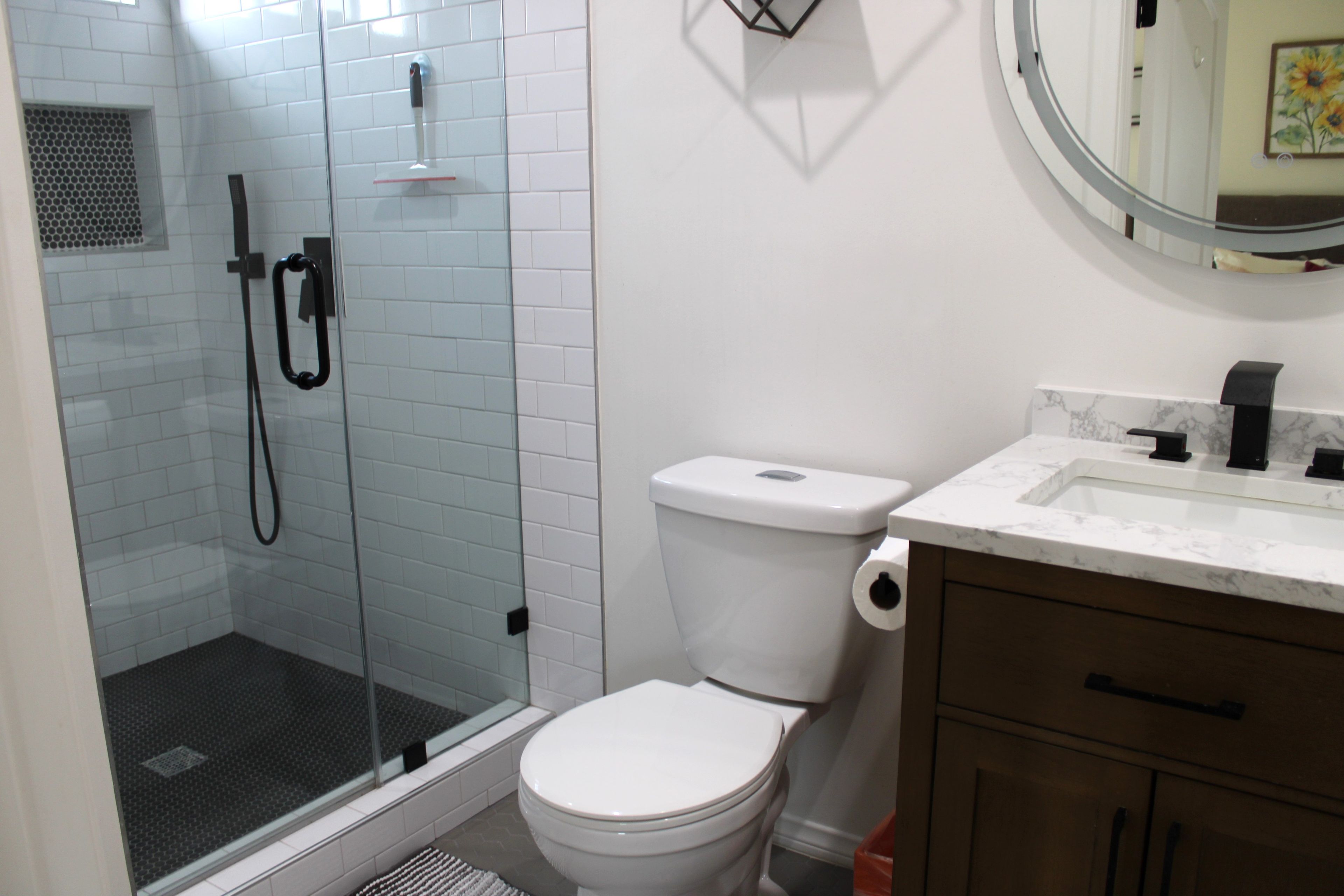 Une salle de bain avec une douche à parois de verre, des toilettes blanches et un comptoir en marbre.