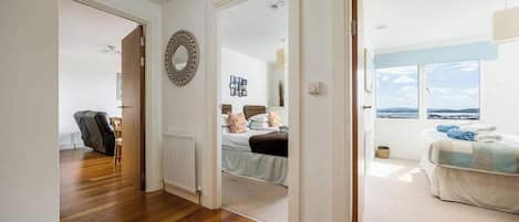 Una habitación amplia con suelo de madera, cama con vistas y un espejo grande en la pared.