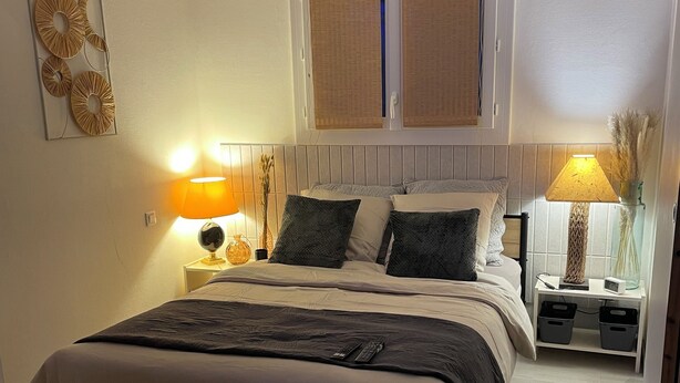 Camera da letto con un letto, lampade da comodino, un comodino e un condizionatore d'aria a parete.