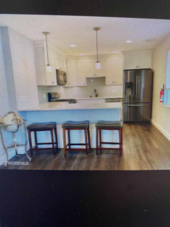 A room with a wooden floor, a black cabinet, and two wooden tables.