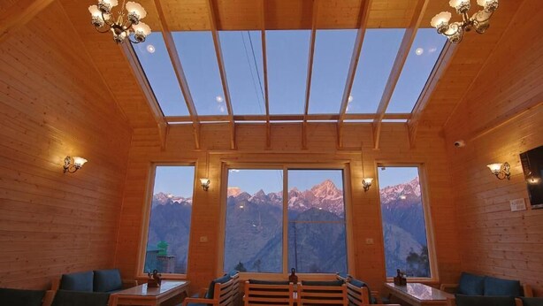 A wooden interior with a skylight, large windows, and seating. - The Auli Meadows (Joshimath)