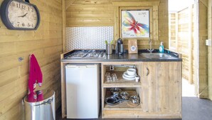 A compact kitchen with a stove, refrigerator, and a sink. There's a clock on the wall and a decorative butterfly poster. - Beachside Dune Home Retreat for 4 (Almere)