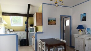 Eine Küche mit Essbereich, Kühlschrank, Mikrowelle, Spüle und Fenster.