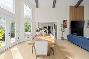 Ein geräumiges Wohnzimmer mit einem großen Holzesstisch, einem blauen Sofa und einem Kamin.