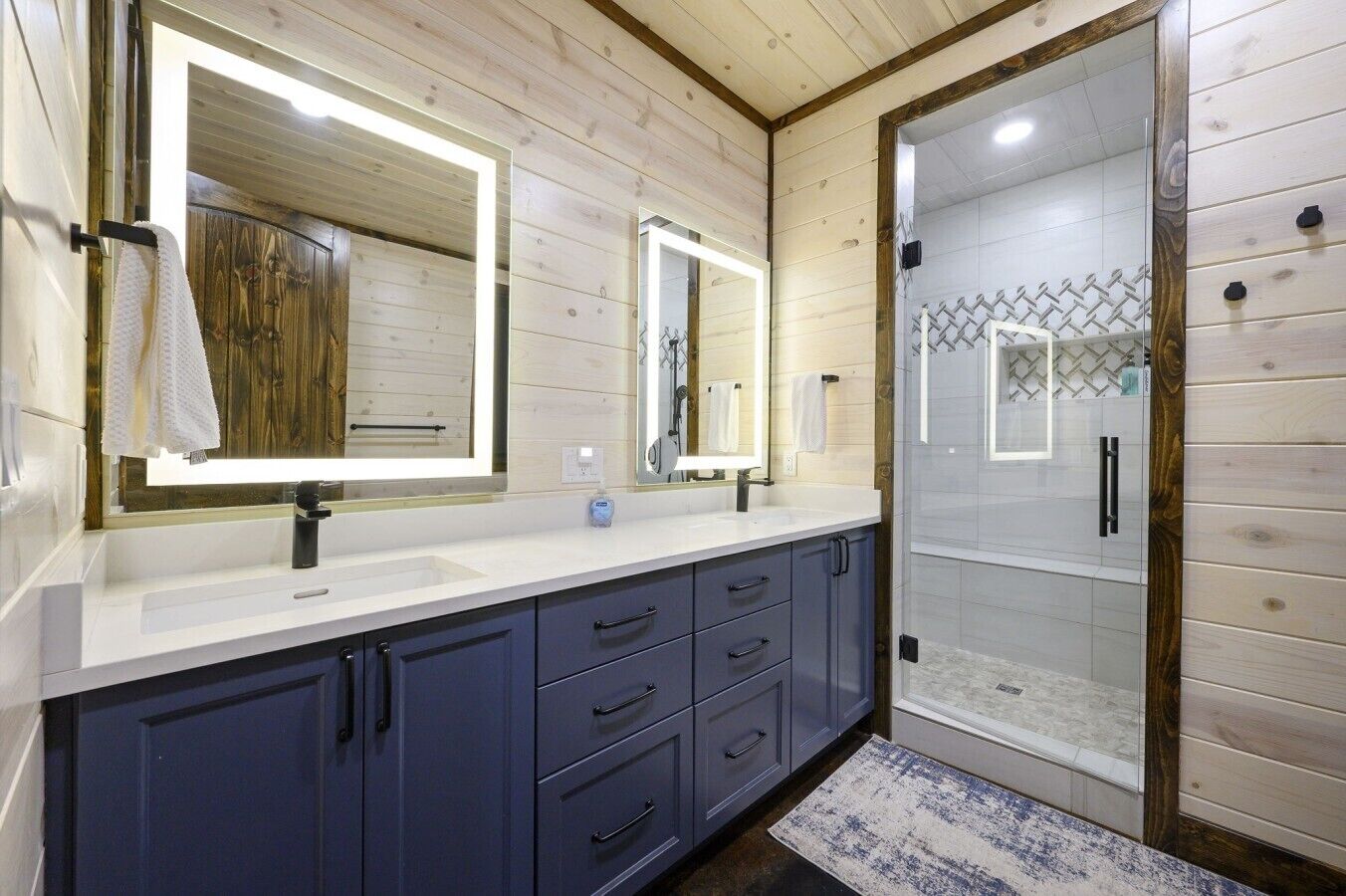 Un bagno moderno con rivestimenti in legno, un mobile doppio lavabo e una cabina doccia in vetro.
