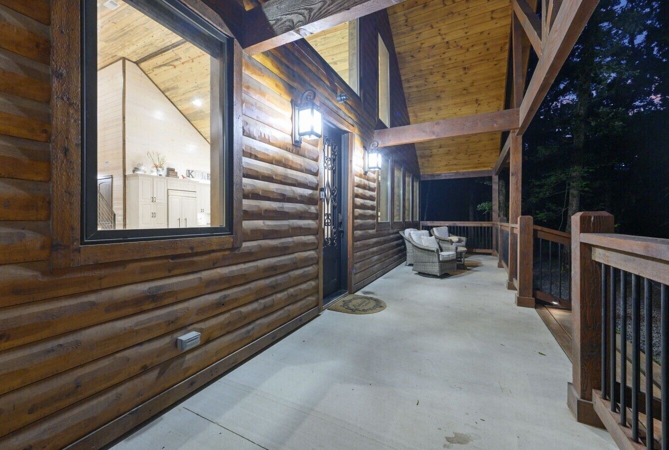 A wooden cabin with a covered porch, a door leading to a room, and outdoor seating.