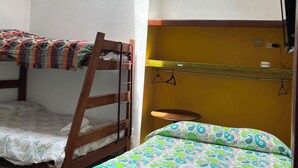 A dormitory room with bunk beds, a small table, and a chair.