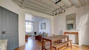 Um quarto espaçoso com uma mesa de jantar de madeira, lareira e uma janela grande.