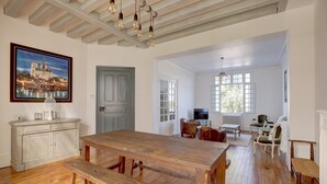 Um quarto amplo com uma mesa de jantar de madeira, um armário branco e uma pintura de um castelo.