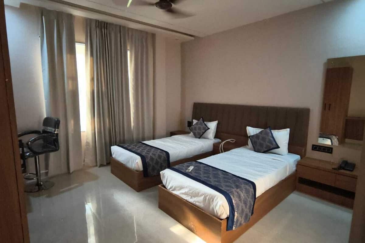 A hotel room with two beds, a chair, a desk, and a mirror.