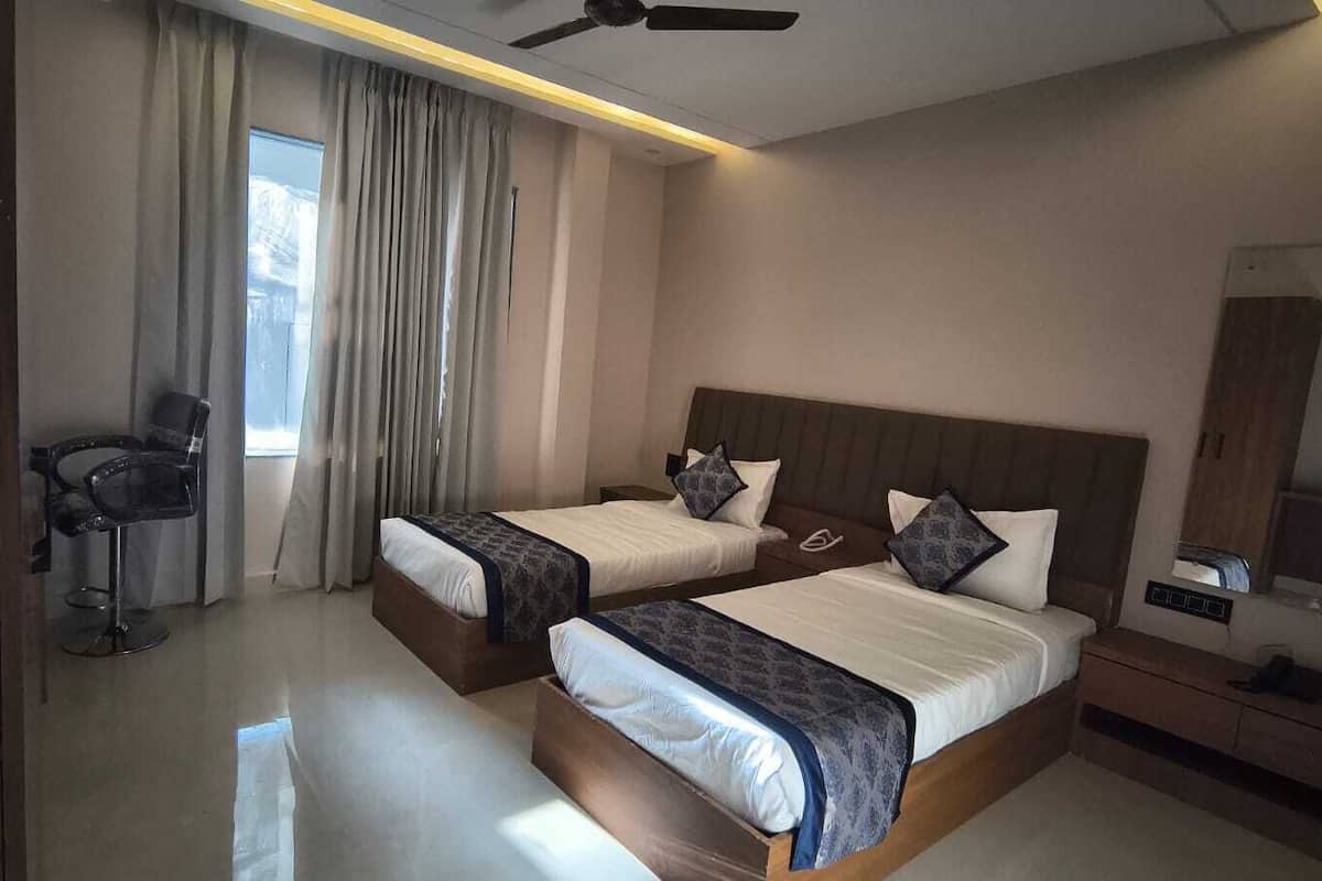 A hotel room with two beds, a ceiling fan, a mirror, and a chair.