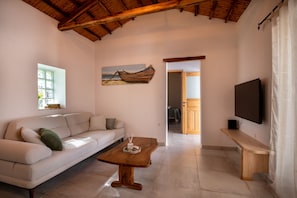 Una sala de estar con un sofá, una mesa de centro de madera, un televisor de pantalla plana y un cuadro en la pared.