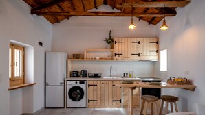Eine kleine Küche mit Holzausstattung, einer Waschmaschine und einem Barhocker.