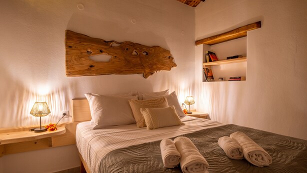 Ein Schlafzimmer mit einem großen Bett, zwei Nachttischen, einem hölzernen Kopfteil und einem Regal mit Büchern.