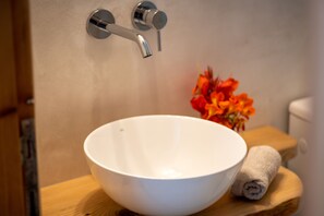 A white basin on a wooden tray, a towel, and a flower arrangement in a bathroom. - Yiayia's House (Alonnisos)