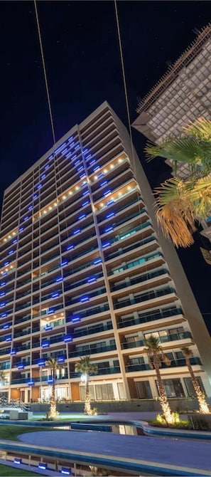 Un hôtel à plusieurs étages au design moderne, doté de balcons et d’un espace piscine.