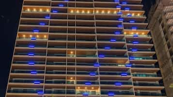 A multi-story hotel with a modern design, featuring balconies and a distinctive lighting pattern on the facade.