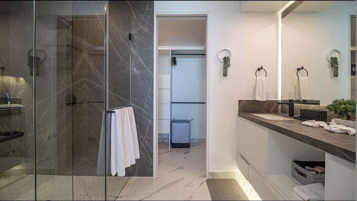 Un bagno moderno con box doccia in vetro, lavabo con specchio e portasciugamani.