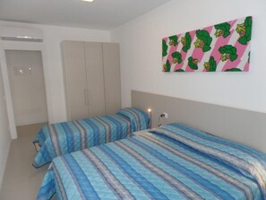 Una camera da letto con due letti, un armadio e una parete con un motivo colorato.