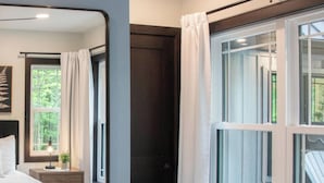 A bedroom with a bed, bedside table, lamp, and a window with curtains.
