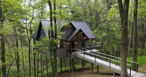 A treehouse with a balcony, surrounded by a forest.
