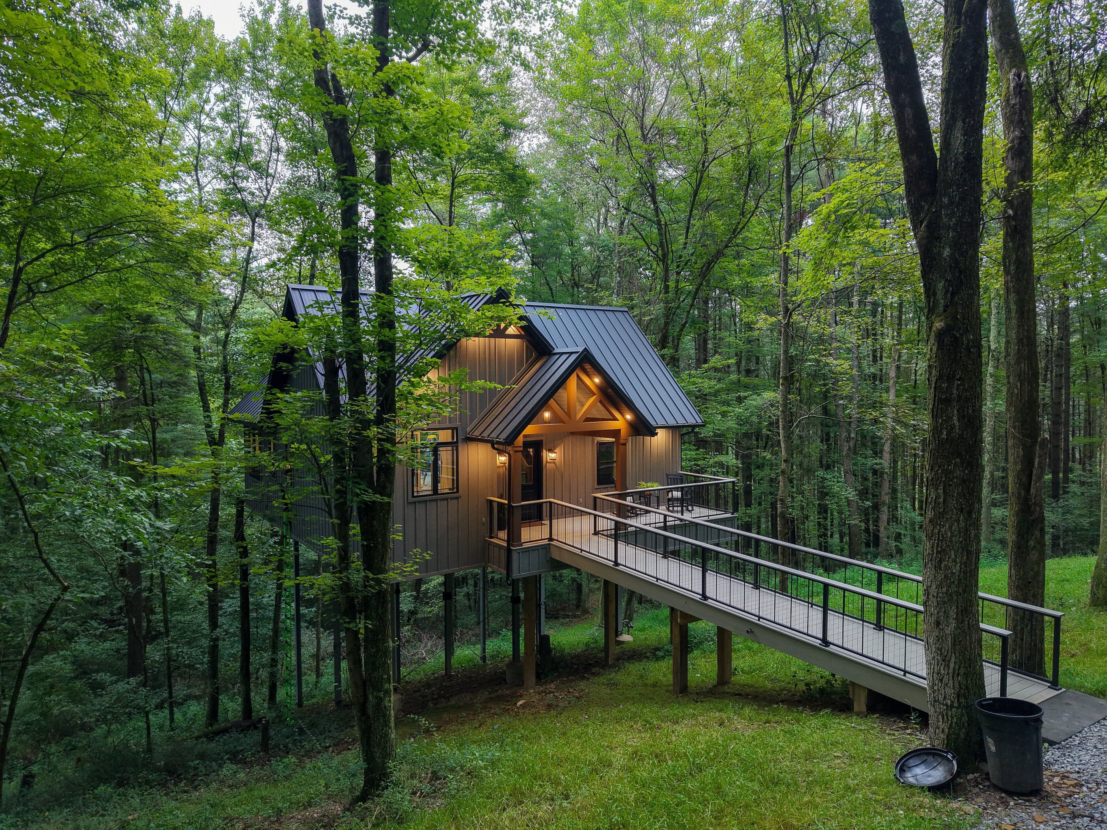 A cabin with a wooden exterior, a balcony, and a staircase leading to the entrance.