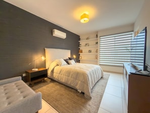 A bedroom with a bed, bedside tables, a TV, and a window with blinds. - Lujosa casa de 3 cuartos (Jardines de la Silla)