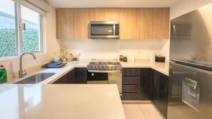 Una cocina moderna con microondas, estufa y refrigerador integrados.