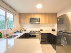 A modern kitchen with a built-in microwave, stove, and refrigerator. - Lujosa casa de 3 cuartos (Jardines de la Silla)