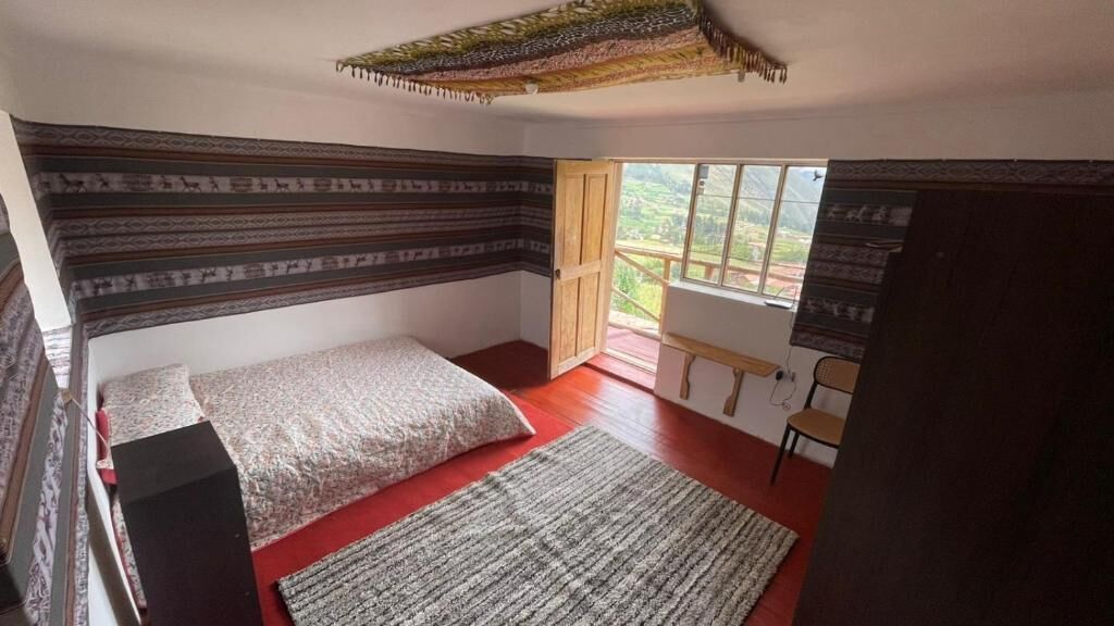 A bedroom with a bed, a rug, a desk, and a window with a view.