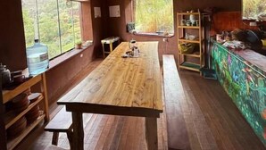Un interior rústico de madera con una gran mesa de comedor, bancos y un mural colorido en la pared.