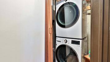 A stacked washer and dryer unit with a wooden door frame.