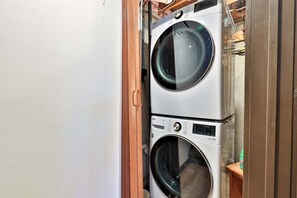 A stacked washer and dryer unit with a wooden door frame. - Liquid Lodge Upper: 4BR Duplex with Hot Tub and 1 PM Checkout (Killington)