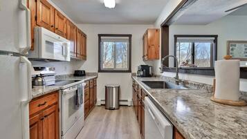 A kitchen with wooden cabinets, a stainless steel sink, a microwave, and a stove.