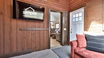 A wooden interior with a mounted sign, a door, a sofa, and a rug.