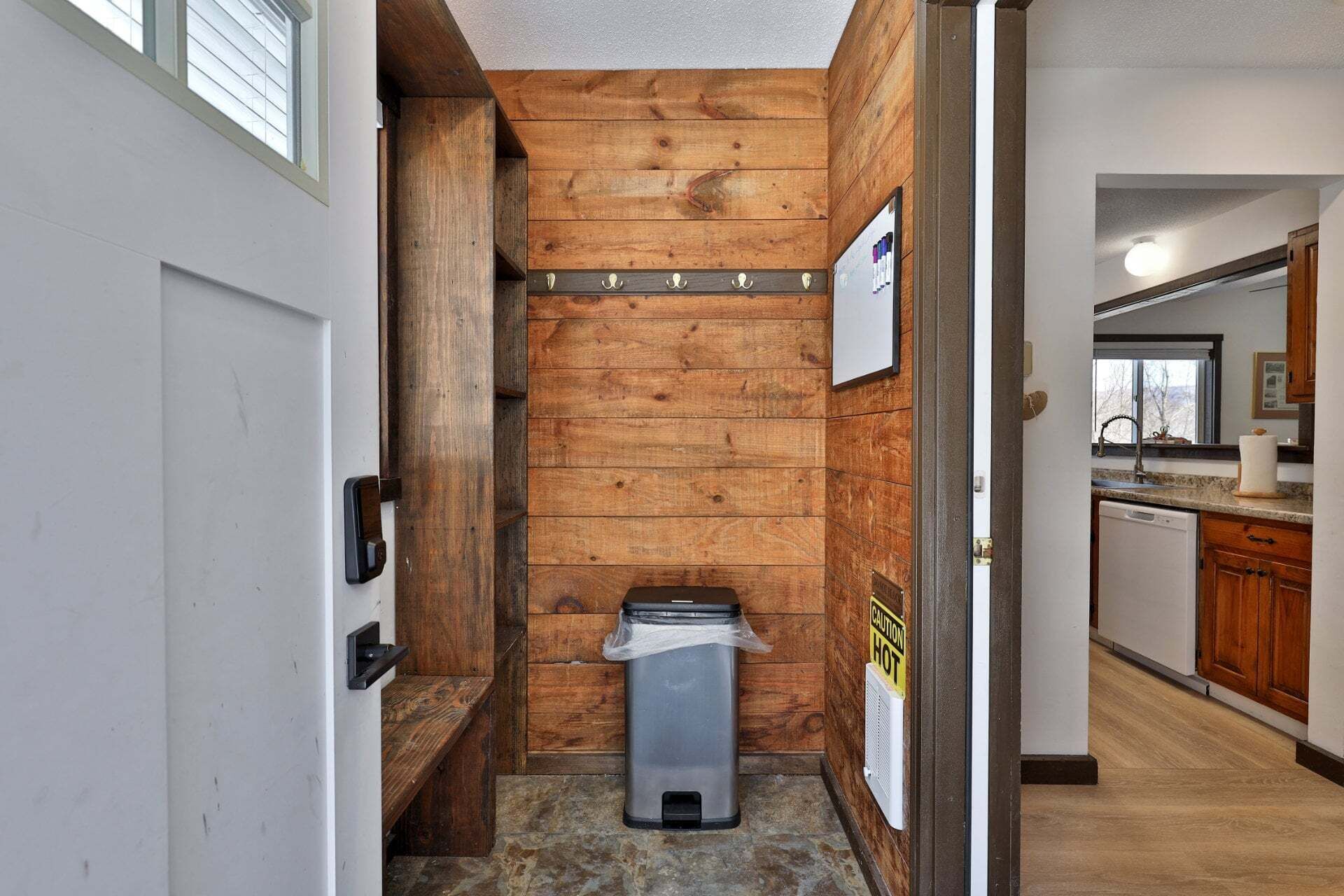 A narrow hallway with wooden walls, a trash bin, and a caution sign.