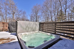 Ein Whirlpool im Freien mit Holzzaun und Bäumen ohne Blätter im Hintergrund.
