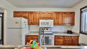 A kitchen with wooden cabinets, a white refrigerator, a microwave, a stove, and a toaster.