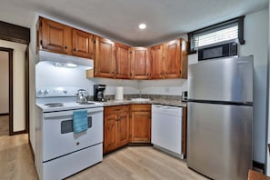 A kitchen with wooden cabinets, a stainless steel refrigerator, a stove, and a dishwasher. - Liquid Lodge Lower: 2BR Duplex near Killington with 4 PM Checkout (Killington)