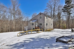 A two-story house with a covered porch, surrounded by a snowy landscape and trees. - Liquid Lodge Lower: 2BR Duplex near Killington with 4 PM Checkout (Killington)