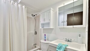 A bathroom with a shower, toilet, sink, and cabinets. - Liquid Lodge Lower: 2BR Duplex near Killington with 4 PM Checkout (Killington)