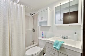 Ein Badezimmer mit Dusche, Toilette, Waschbecken und Schränken.